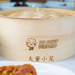 Bamboo steamer featuring DD Soup Dumpling logo with Chinese text, close up.