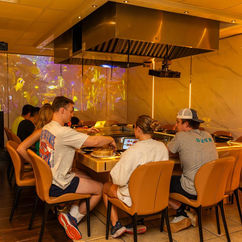 Group of people dining at a teppanyaki restaurant, enjoying a meal.